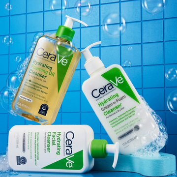 A blue tiled bathroom with floating bubbles. CeraVe Hydrating Foaming Oil floating covered in bubbles. Hydrating Cream o Foam Cleanser slow getting lifted by bubbles. Horizontal laying sideways CeraVe Hydrating Facial Cleanser