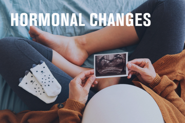 Pregnant woman holding an ultrasound photo, symbolizing hormonal changes and motherhood.