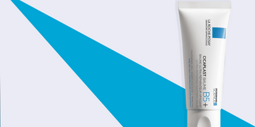 A La Roche-Posay Cicaplast Baume B5+ skincare product in a white tube with blue accents, displayed against a light background with a bold blue geometric design.